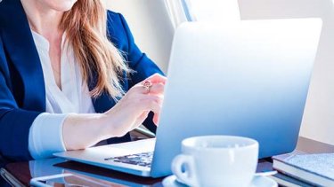 A person types on a laptop while onboard a plane