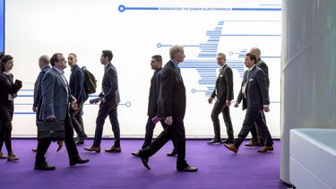 A group of people walk in front of a white sign at AIX