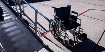 An empty black wheelchair beside a ramp at an airport