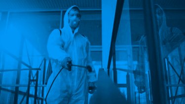 A man in a protective suit disinfecting the building