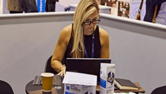 woman with eye glasses sitting on a chair and typing on her laptop